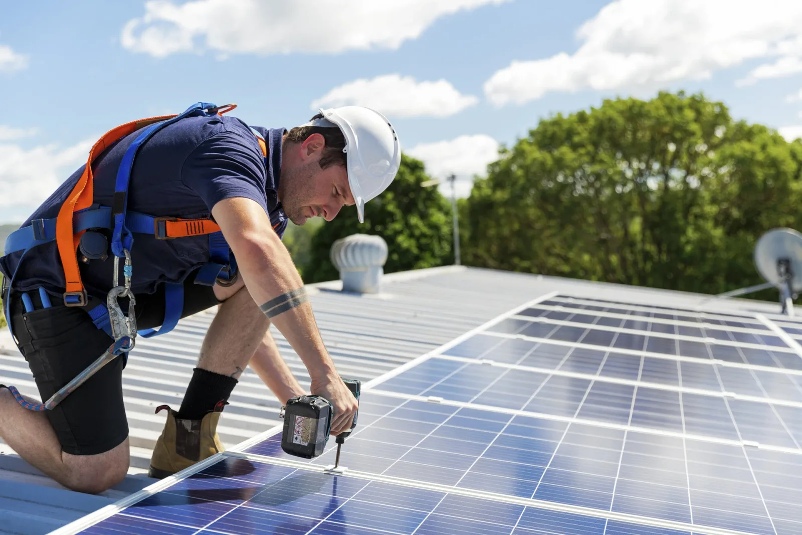Solar technician working on solar panels on a metal roof.