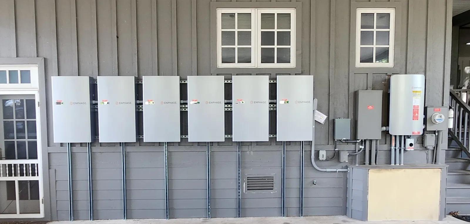 Residential Enphase backup batteries mounted on an exterior wall for home energy storage.
